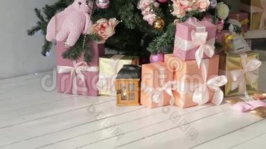 圣诞礼物立在树下。 粉红色和橙色的盒子，有浅色丝带